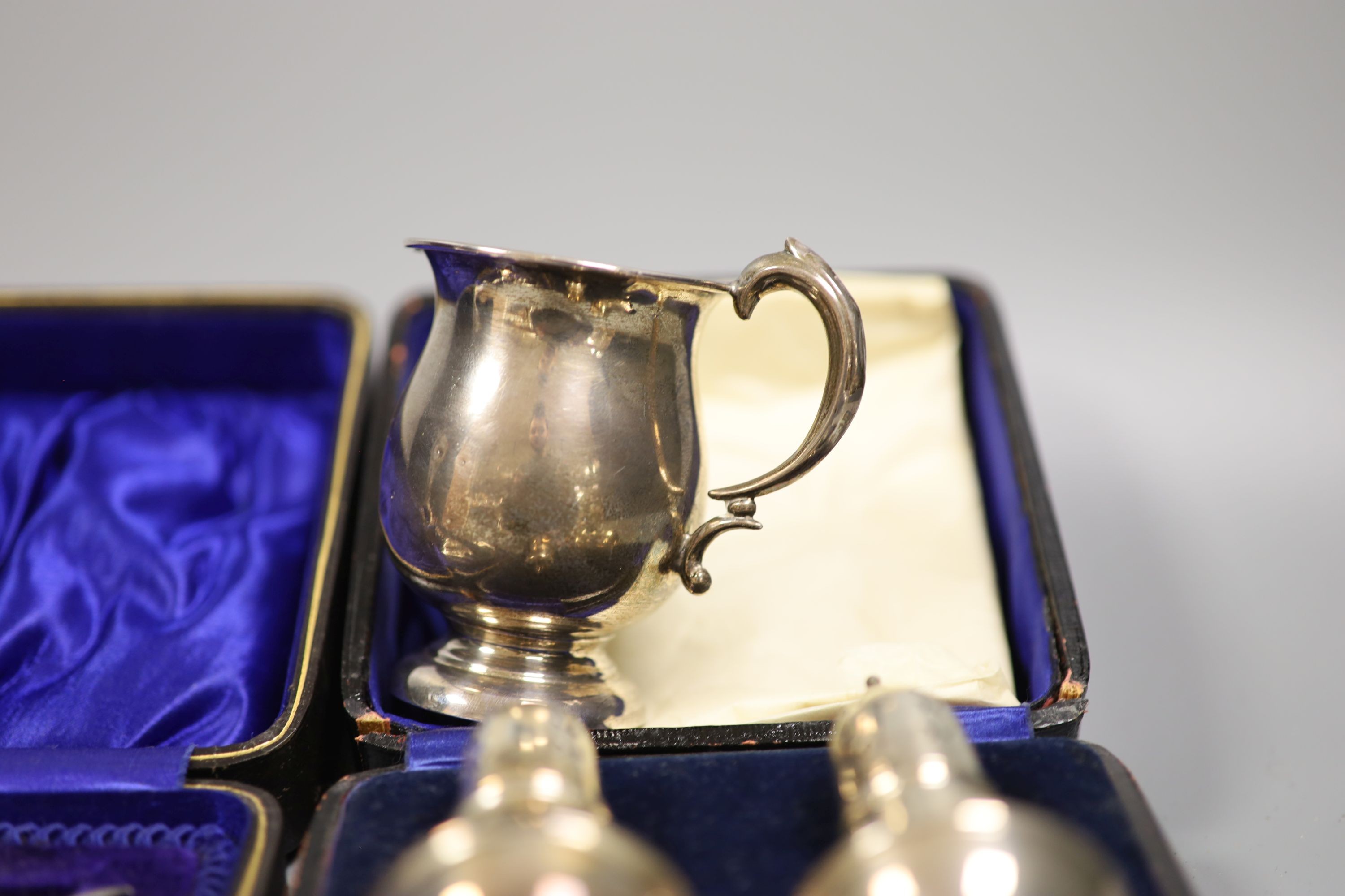 A 1920's silver small mug, a cased pair of silver pepperettes and a cased pair of knife rests and fork.